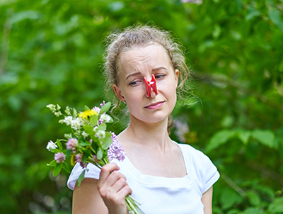 Photo of woman with her nose clipped holding a bouquet of flowers