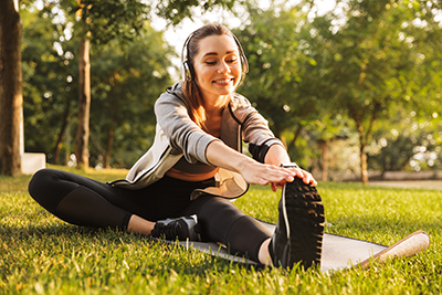 Photo of woman stretching while listening to audio courses in the park