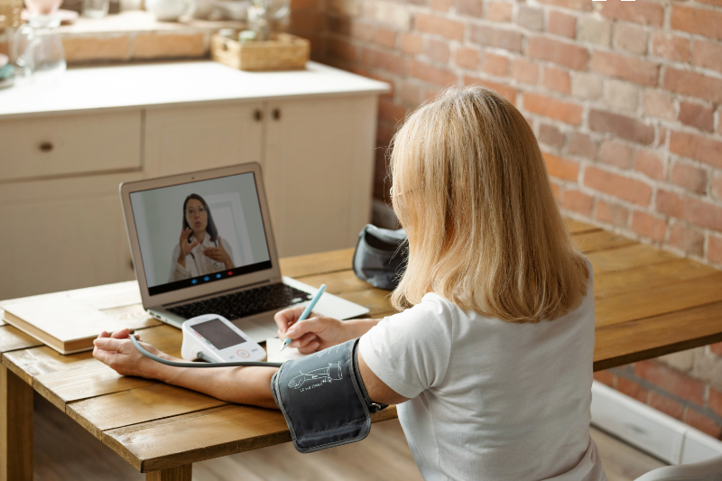 photo of female using bluetooth blood pressure cuff and using laptop