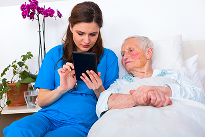 Photo of nurse sitting next to patient using a tablet