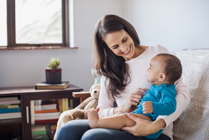 photo of woman sitting with baby on lap