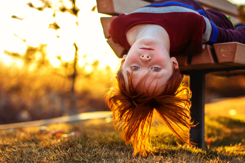 photo of little boy upside down on bench