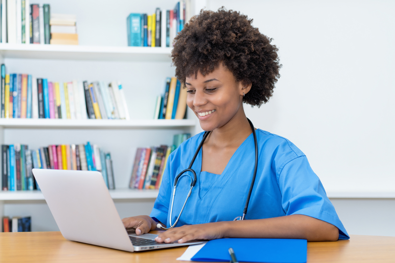 Photo of nurse sitting at computer happy