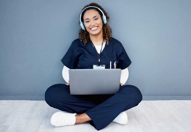 Photo of nurse sitting on the floor with her laptop smiling