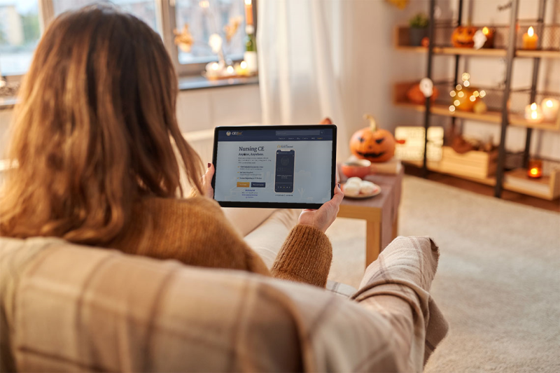 Photo woman sitting on her couch holding a tablet completing her ceus